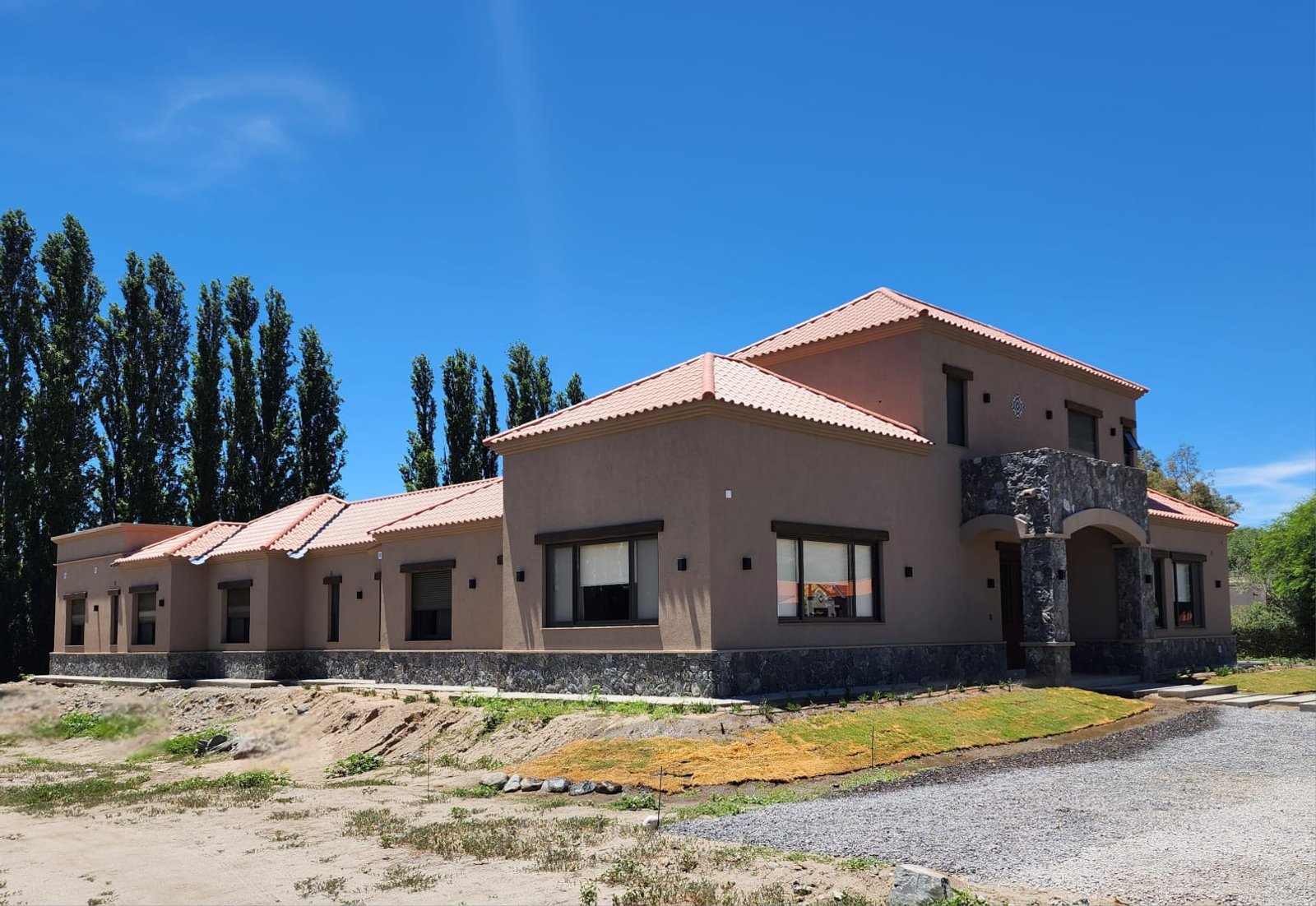 Fachada de casa rural mediterránea moderna con detalles de arcos — proyecto Ca La Estancia, por Luciana González Anderson, en Cafayate